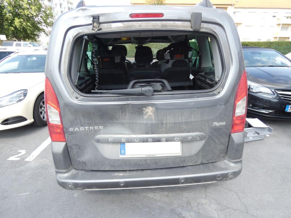 Grauer Peugeot Partner mit eingeschlagener Heckscheibe und beschädigter Heckklappe