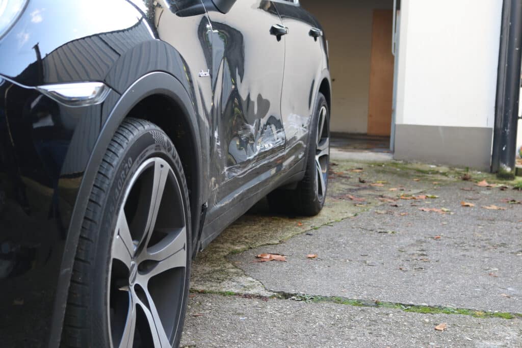 Seitenschaden an einem schwarzen SUV bei der Begutachtung vor Ort