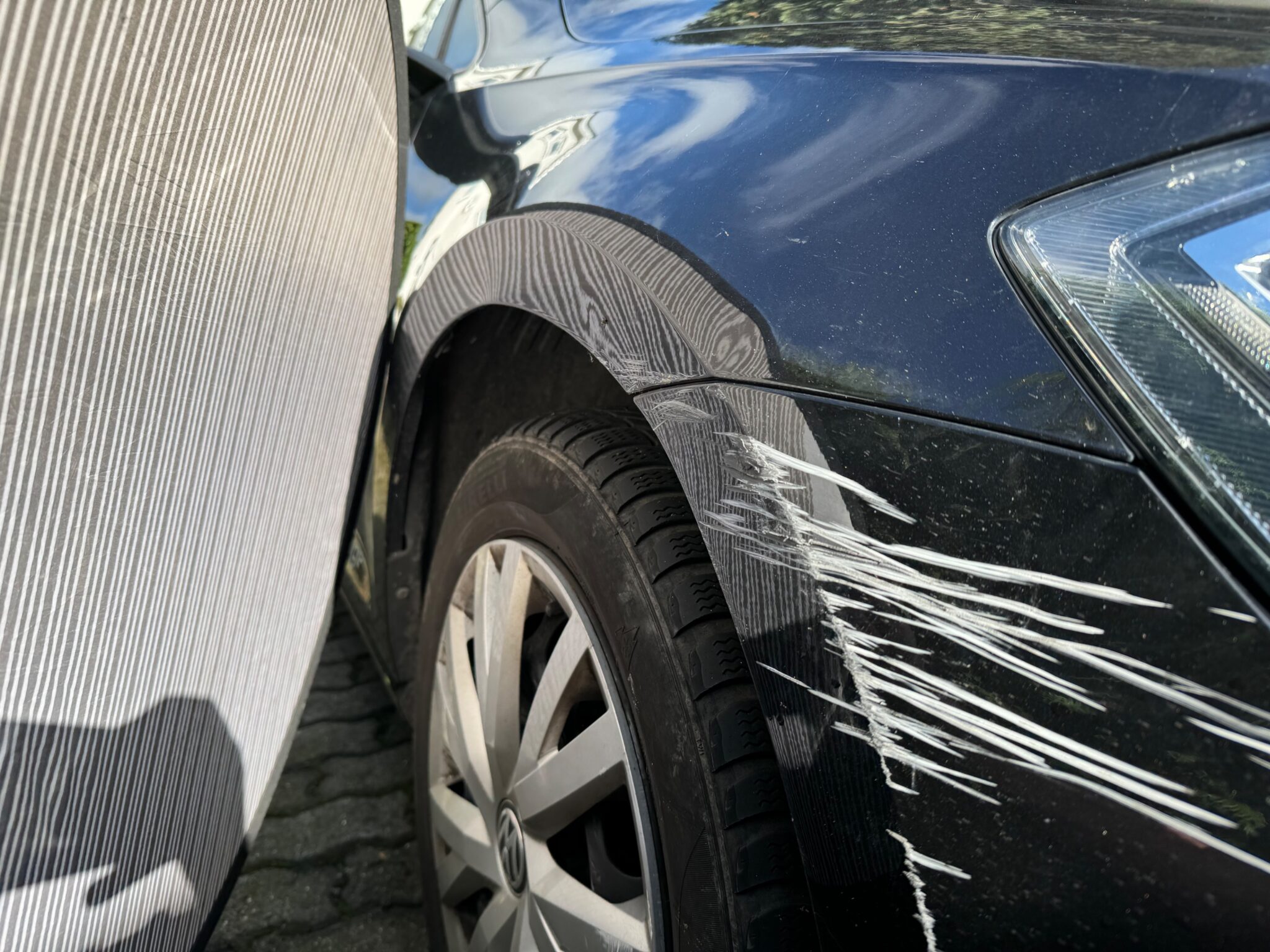 Dellensegel macht die Verformung am Kotflügel sichtbar – Stoßfänger mit tiefen Kratzern und Materialabtrag